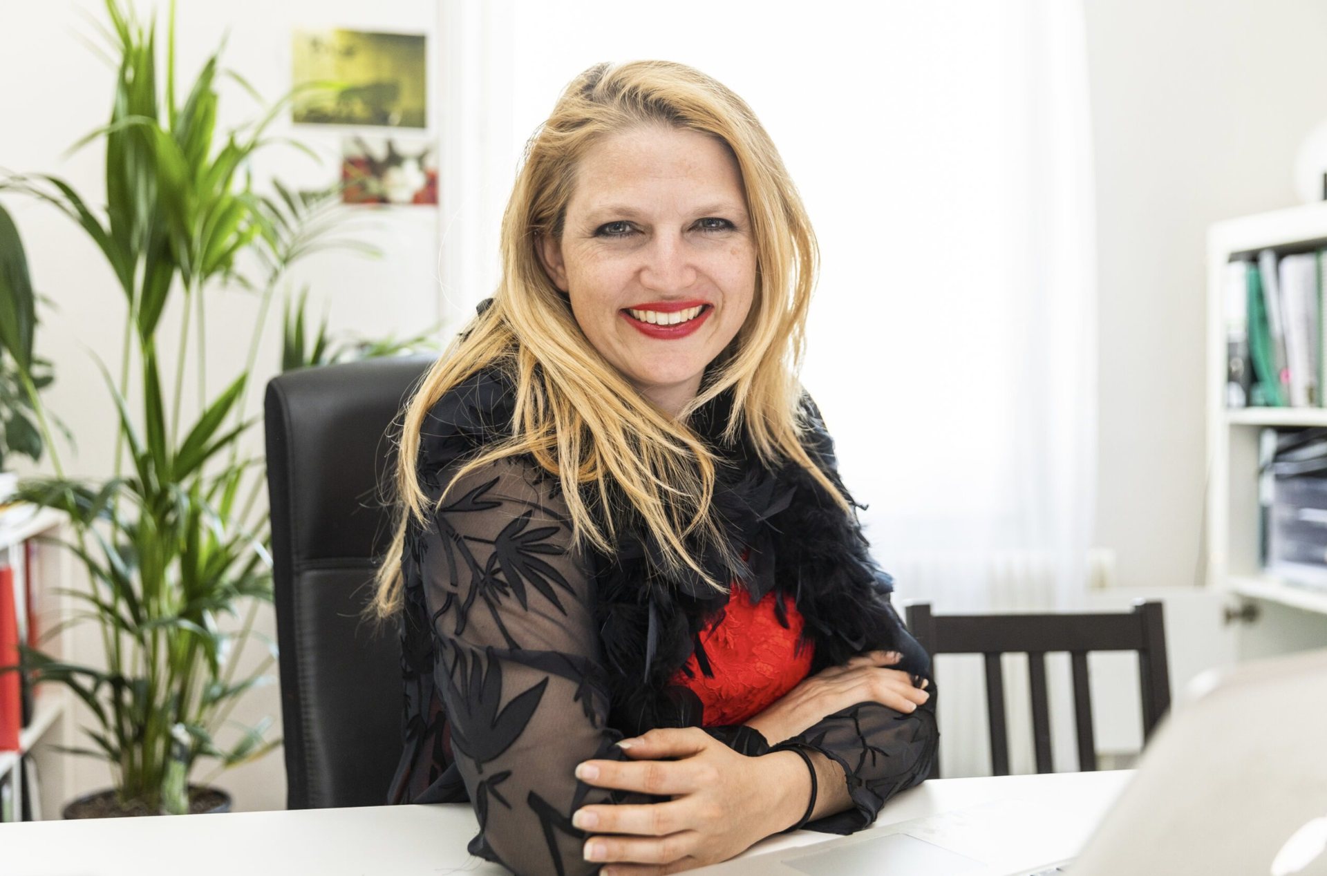 Nathalie Sameli lächelt im schwarzen Blazer an ihrem Laptop