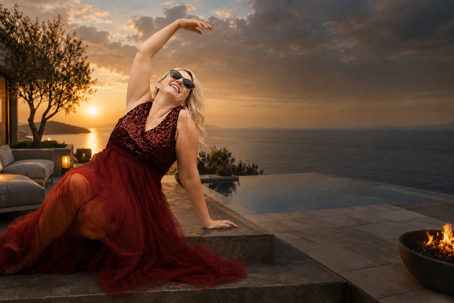 Nathalie Sameli im roten Kleid auf einer Terrasse am Meer bei Sonnenuntergang